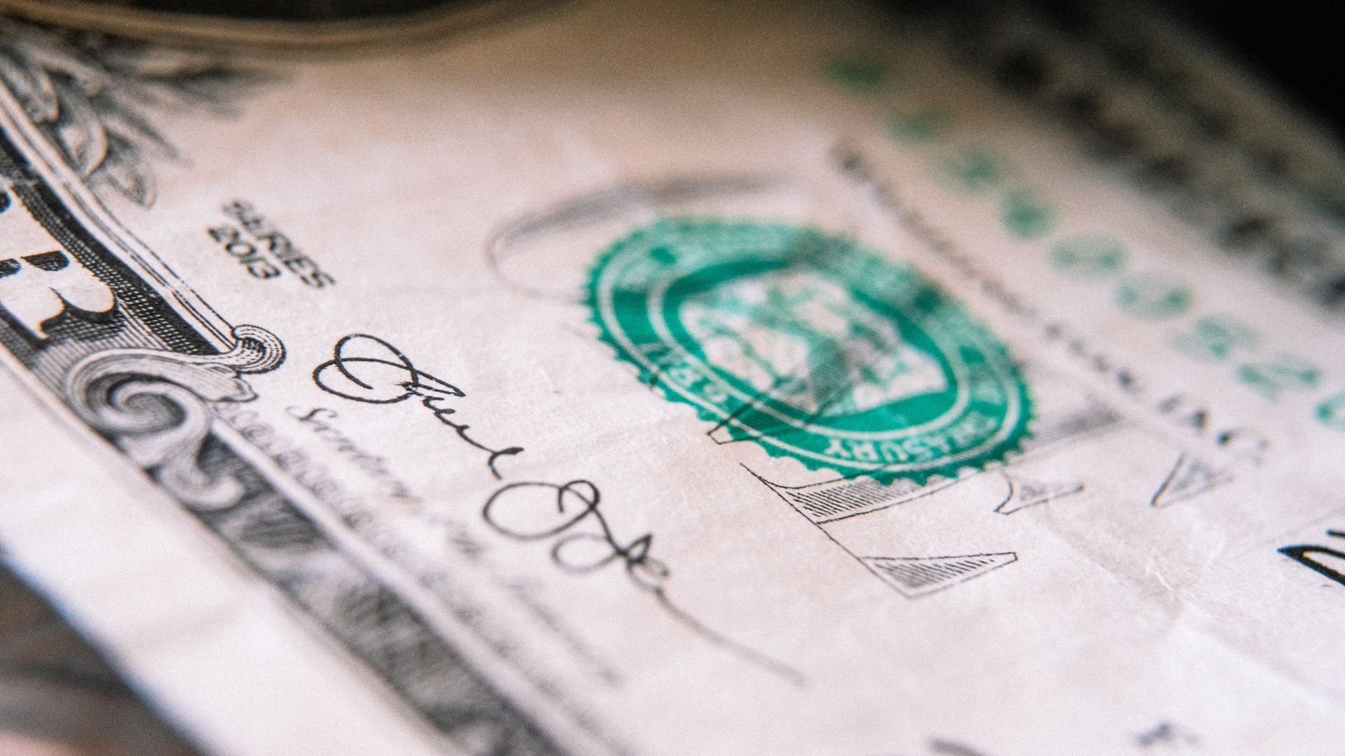 Close-up of US dollar bill showing green seal and detailed engraving