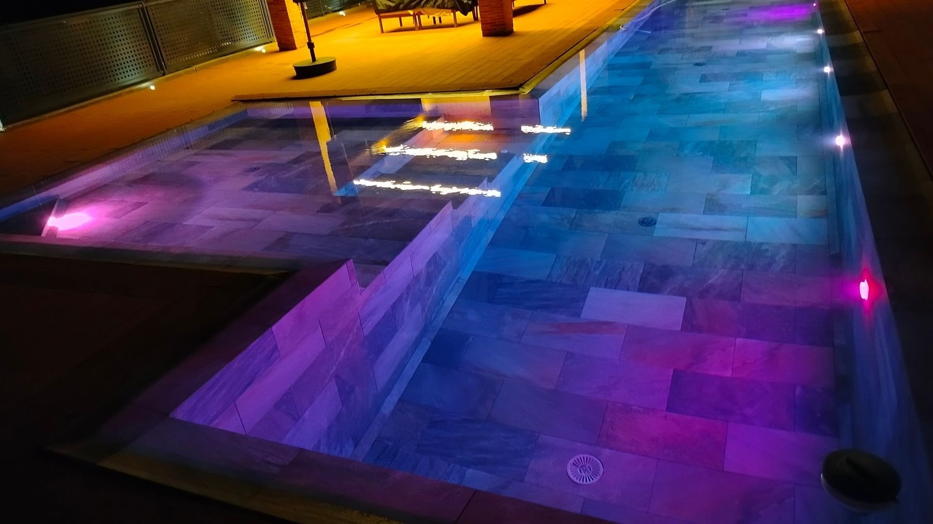 Modern underground parking garage illuminated with neon purple and blue lighting at night.