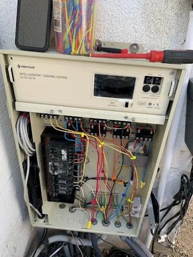 Pentair intelligent control system mounted on wall with exposed circuitry and colorful wiring