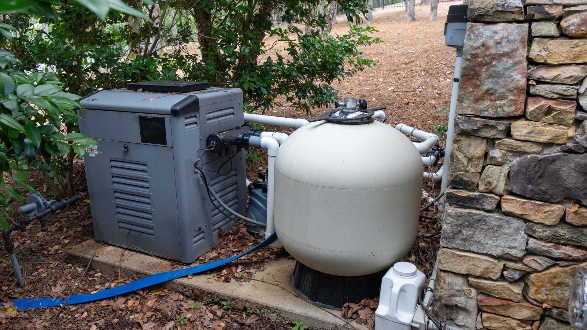 Swimming pool heat pump and filter system installed in a residential backyard.