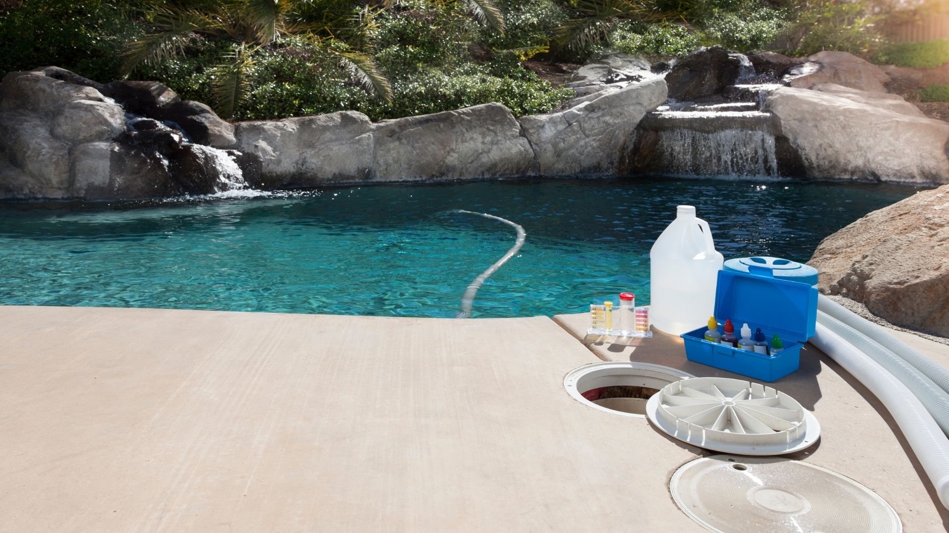 Pool deck with chemicals and maintenance supplies overlooking turquoise water and rocky landscape